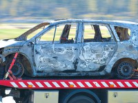 Wrecked and burnt car being trnsported by pick up truck