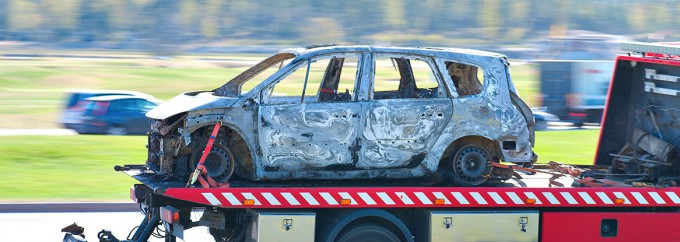 Wrecked and burnt car being trnsported by pick up truck